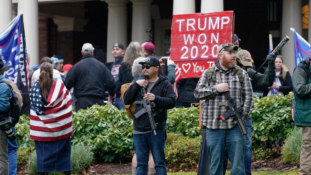 Pendukung Trump menenteng senjata api di luar Istana Gubernur setelah menerobos pagar pembatas, Rabu, 6 Januari 2021, di Capitol, Olympia, Washington. AP / Ted S. Warren