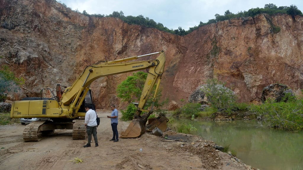 Petugas berpakaian preman mengamankan satu unit ekskavator