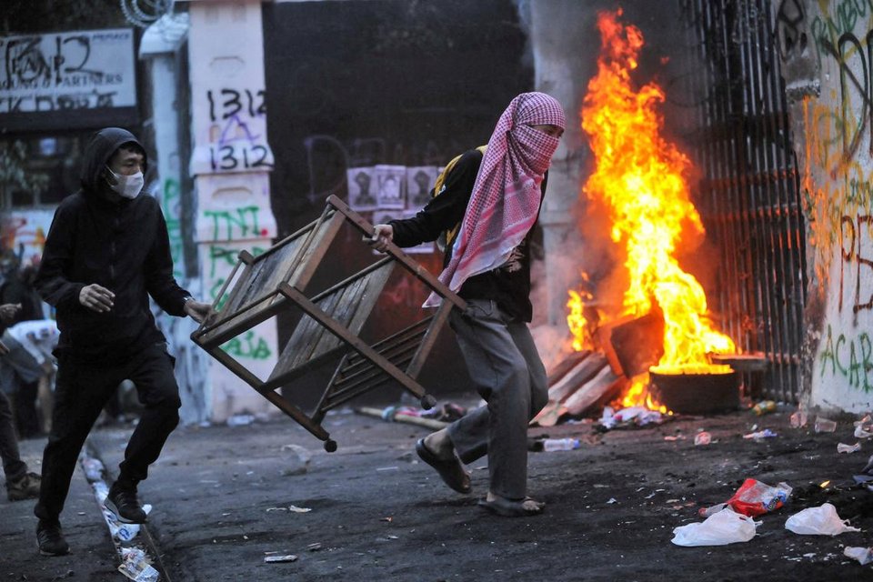 Protesters carry items to be burned outside the regional parliament building in Bandung
