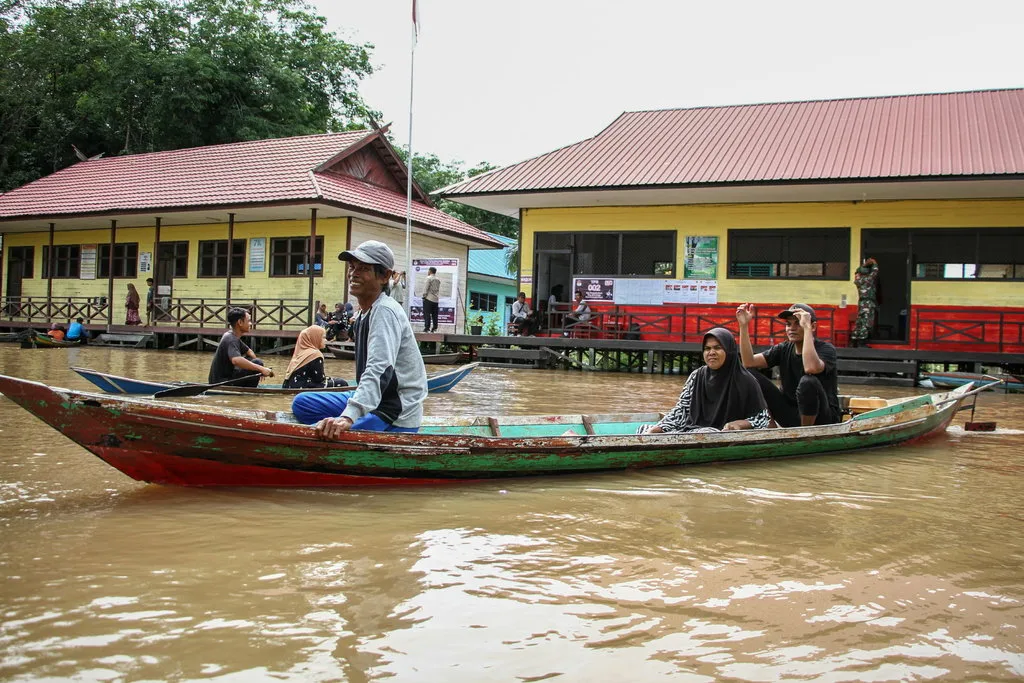 Warga menaiki perahu motor usai melakukan pencoblosan